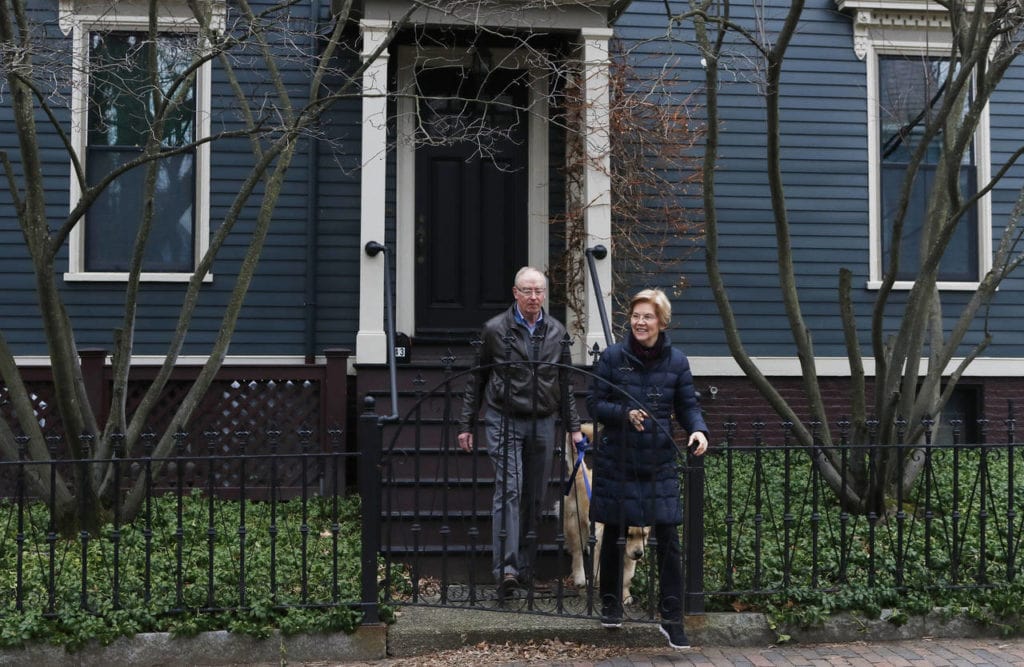 Senator Elizabeth Warren steps outside her home with her husband Bruce Mann and their retriever Bailey